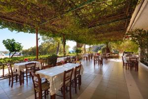 um restaurante vazio com mesas, cadeiras e árvores em Dionyssos Rooms Preveli Crete em Preveli