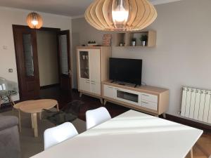 a living room with a television and a table and chairs at PASEO SAN PEDRO - Garaje, Ascensor, 6-8 pers - Dispo 15 al 30 Junio min 3 noches in Llanes