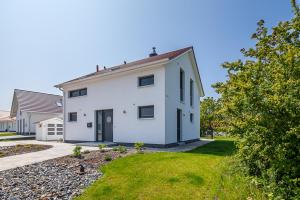 a white house with a driveway and a yard at Ferienhaus Rügen-Relax in Trent