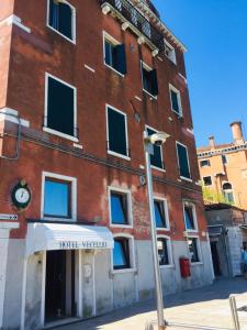 ein großes Backsteingebäude mit einer Uhr drauf in der Unterkunft Hotel Vecellio Venice on the Lagoon in Venedig