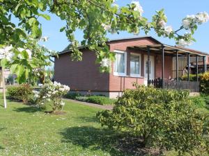 una casa con un árbol en el patio en Strandbungalow, Boltenhagen, en Boltenhagen