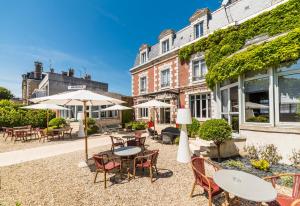 an outdoor patio with tables and chairs and umbrellas at The Originals Boutique, Hôtel Normandie, Auxerre in Auxerre +85 photos