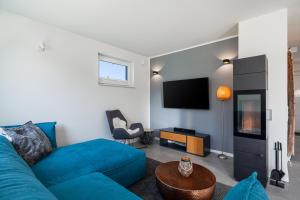 sala de estar con sofá azul y TV en Ferienhaus Rügen-Relax, en Trent
