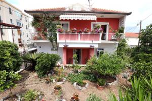 una casa roja y blanca con plantas en el balcón en Stela Apartments, en Trogir