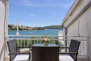 a table and chairs on a balcony with a view of the water at Apartments Ana Bilota in Seget Vranjica