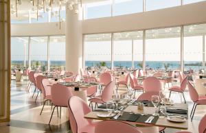 a dining room with pink chairs and tables at NissiBlu Beach Resort in Ayia Napa