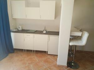 a small kitchen with white cabinets and a sink at Amena Mar Hotel in Sa Coma