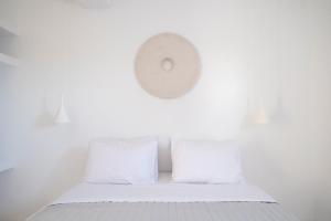 een witte kamer met een bed met witte kussens bij Meltemi Seaside in Kampos Paros