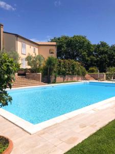 una grande piscina blu di fronte a una casa di B&B Villa FioreConero a Montacuto