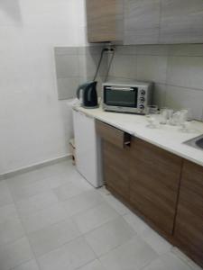 una pequeña cocina con microondas y fregadero en Georgia Beach Apartments, en Mesongi