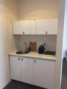 een keuken met witte kasten en een wastafel bij Suite 336 in Menen