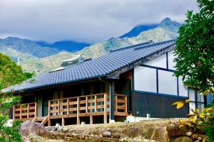 a house with a roof with mountains in the background at South Coast house in Yakushima