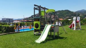 a playground with a slide in the grass next to a pool at Residence Mizar 2 in Pietra Ligure
