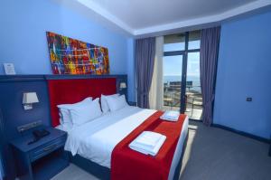 a bedroom with a large bed and a large window at Batumi Palm Hotel in Batumi