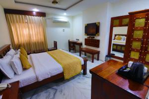 a bedroom with a bed and a desk and a television at Lilypool - The Heritage Jalmahal in Jaipur