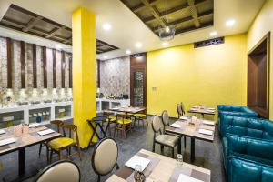 a restaurant with tables and chairs and yellow walls at Hotel Asansol International in Āsansol