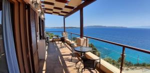 balcón con mesas y sillas y vistas al océano en Villa Vasi, en Porto Heli