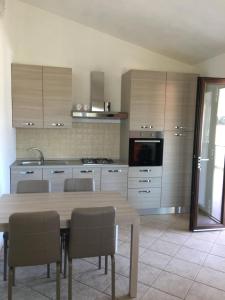 una cucina con tavolo in legno, sedie e un angolo cottura. di Casa Teresa a Porto Pino a Porto Pino Altre 20 foto