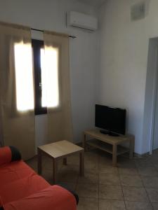 un soggiorno con un divano, una TV e un tavolo di Casa Teresa a Porto Pino a Porto Pino