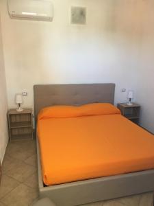 un letto arancione in una stanza con due tavoli di Casa Teresa a Porto Pino a Porto Pino