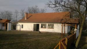 een wit huis met een bruin dak en een hek bij Darutollas Vendégház in Ópusztaszer