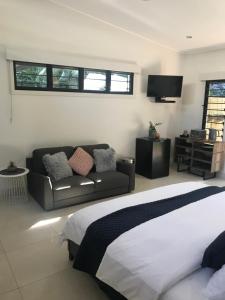 1 dormitorio con cama, sofá y TV en The Tropical Sanctuary, en Darwin