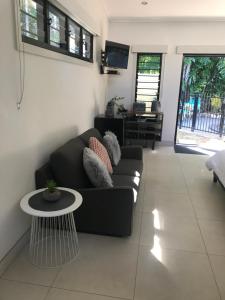 sala de estar con sofá negro y mesa en The Tropical Sanctuary, en Darwin