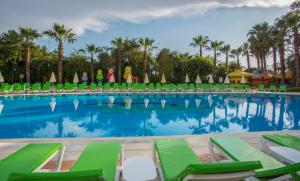 a pool at a resort with green chairs and palm trees at Miarosa İncekum Beach in Avsallar