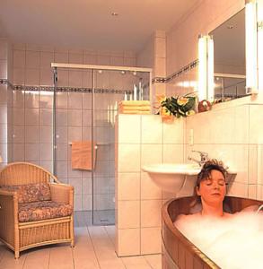 フロートーにあるMoorland Hotel am Senkelteichの浴槽に横たわる女