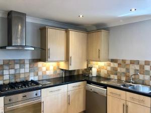 cocina con armarios de madera y horno con fogones en AB - Top floor 2 bed modern town centre apartment with parking for one vehicle en Stratford-upon-Avon