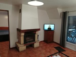 a living room with a fireplace and a television at Chambres d'hôtes Edoniaa in Quend