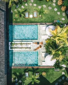 an overhead view of a swimming pool with palm trees at Beyond Bungalows in Canggu
