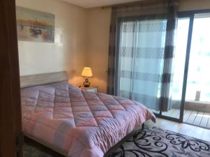 ein Schlafzimmer mit einem Bett und einem großen Fenster in der Unterkunft Appartement Casa-marina au 10ème étage in Casablanca