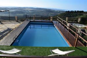 a swimming pool with two chairs and a view of the mountains at Casale Galati in Sciacca