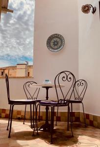 2 Stühle, ein Tisch und eine Platte an der Wand in der Unterkunft Le terrazze segrete in Palermo