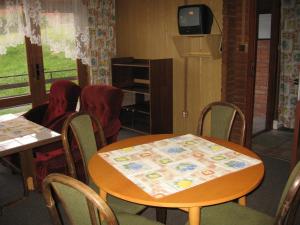 uma sala de jantar com mesa e cadeiras e uma televisão em Chaty u Loveckého zámečku em Buchlovice