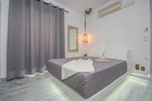 a white bedroom with a bed with a gray blanket at Prestige on the beach in Naxos Chora