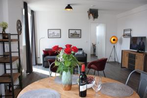 a table with a vase of roses and a bottle of wine at Appartement Altstadtblick im Ohlerich-Speicher in Wismar