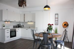 a kitchen with white cabinets and a table with chairs at Appartement Altstadtblick im Ohlerich-Speicher in Wismar