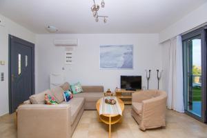 a living room with a couch and chairs and a tv at Haraki Villas in Haraki