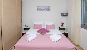 1 dormitorio con 1 cama grande con sábanas y almohadas rosas en Haraki Villas, en Charaki