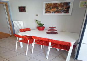 Karditsa Home Sweet Home 80 τ.μ في كارديتسا: طاولة غرفة طعام بيضاء مع كراسي حمراء