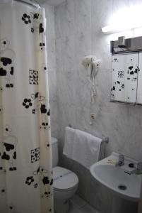 baño con aseo y cortina de ducha con vacas. en Hostal La Perla Asturiana, en Madrid