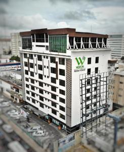 ein weißes Gebäude mit einem grünen Schild darüber in der Unterkunft Weston Suites Hotel in Santo Domingo