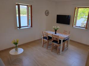 a dining room with a table and chairs and a television at Apartments Stella Apsyrtides in Osor