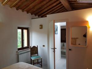 een slaapkamer met een bed, een stoel en een raam bij Luciano & Norma's House La Torre in Massa Marittima