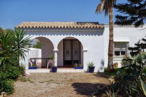 a white house with a palm tree in front of it at Finca Malyma with 2 villas and 1 apartment, beach front 10,000m2 botanic garden in Zahora