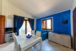 een eetkamer met blauwe muren en een witte tafel en stoelen bij Residence Le Ginestre / Ataras in Porto San Paolo