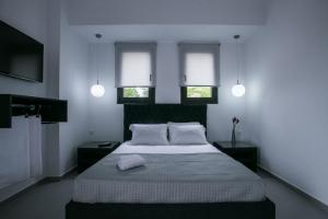 una camera da letto con un grande letto con due finestre di Anemos Luxury Apartments a Agios Nikolaos