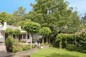 una casa con árboles y plantas en el patio en Bed and Breakfast Het Dijkhuis Eersel, en Eersel